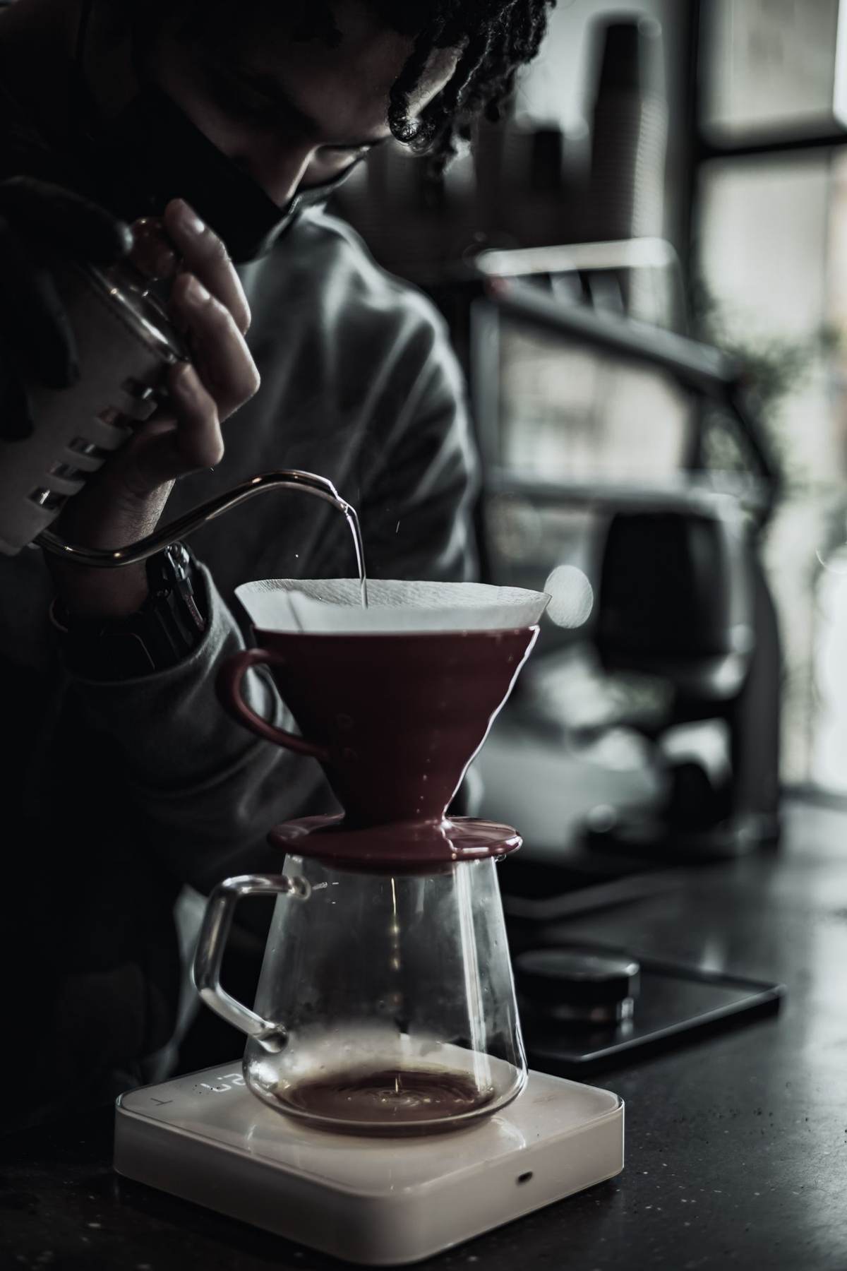 En barista brygger filterkaffe over en glaskande