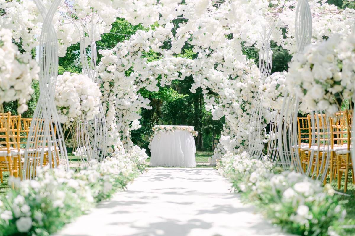 En lysegang mellem stole og en blomsterbue