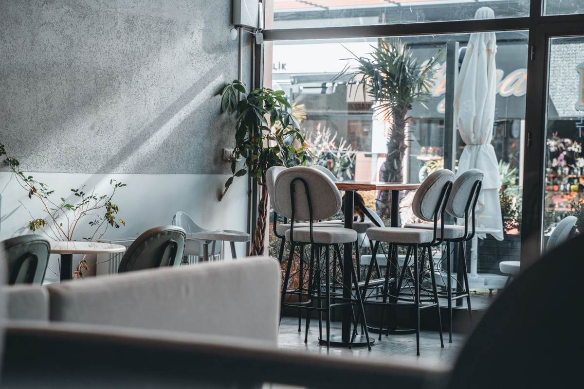 Café-indretning med borde, planter og store vinduer
