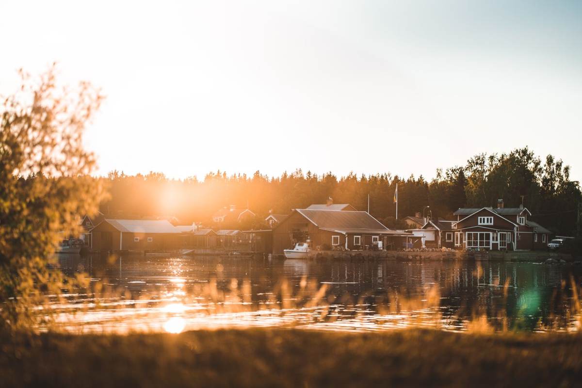 Hytter ved en sø i modlys fra den lave sol