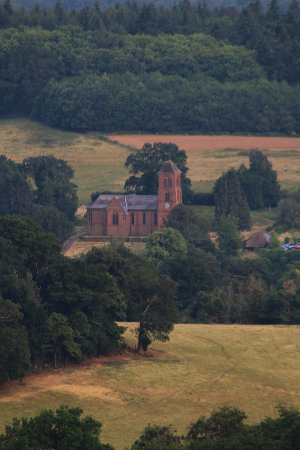 Lille kirke omgivet af skov og marker set fra oven