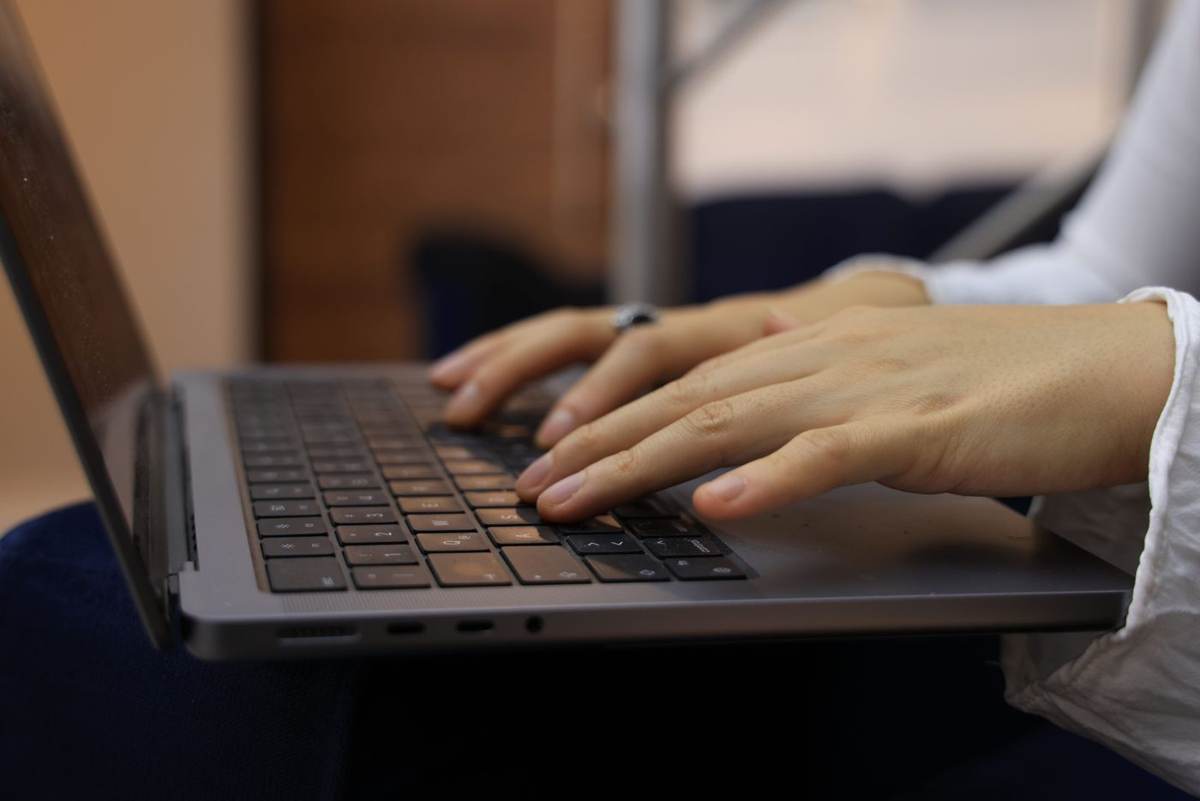 Hænder skriver på et bærbart tastatur i varmt, dæmpet lys