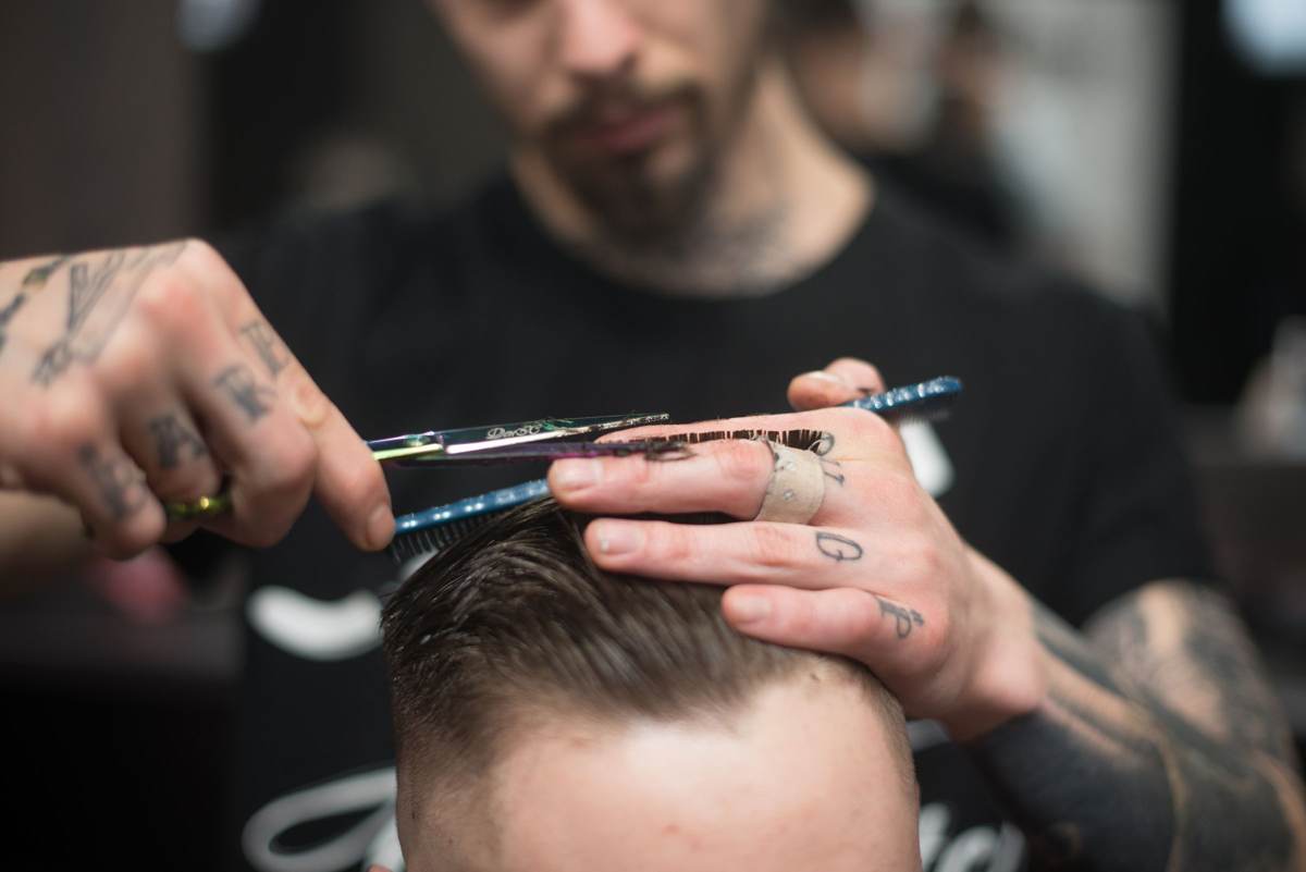 Barber klipper en mands hår med saks og kam