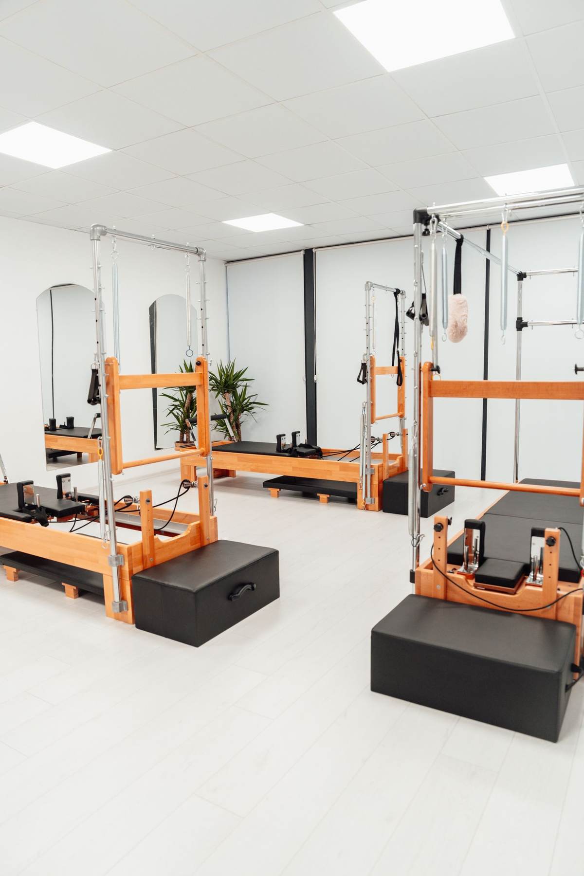 Et lyst pilatesstudie med træreformere og en sort træningsklods