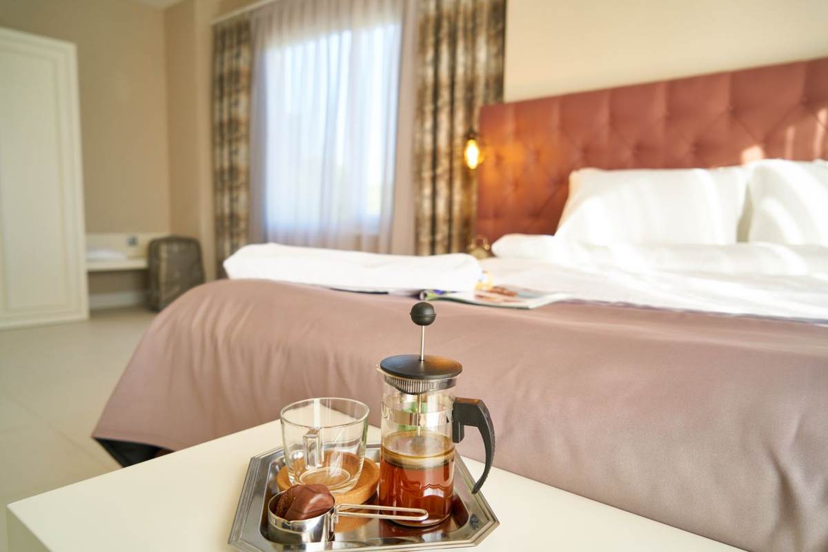 Hotelværelse med en seng og en glaskande te på en bakke i forgrunden