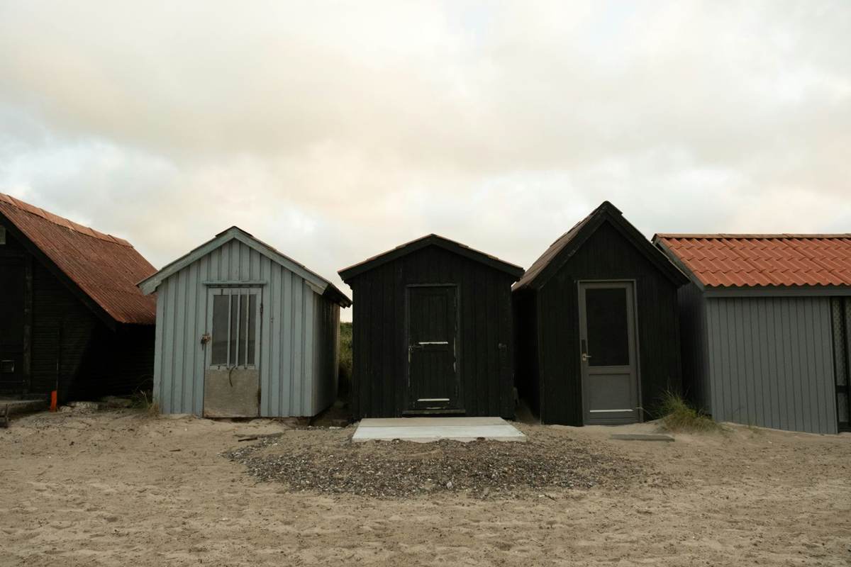Række af træskure på en sandet strand