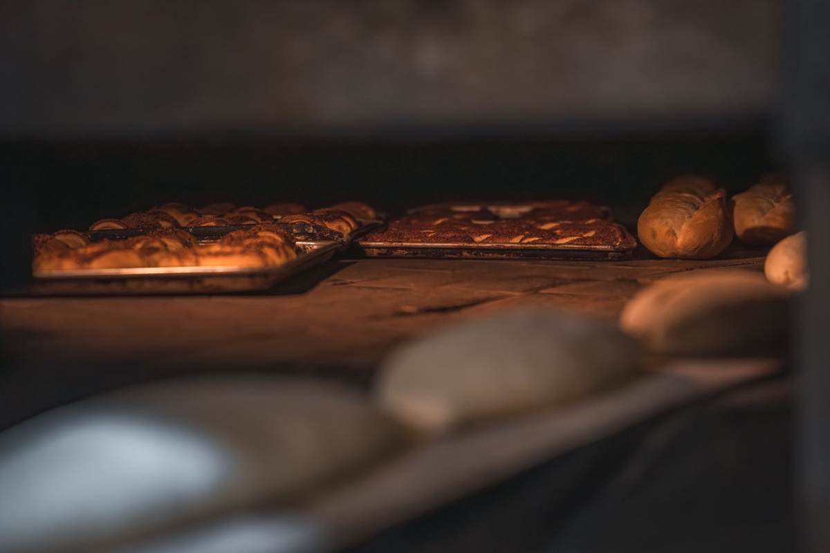 Bagte brød og en plade med bagværk i en mørk ovn