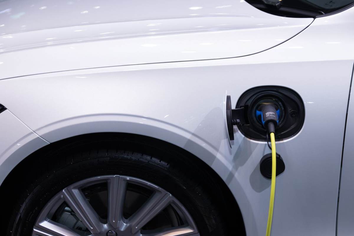Hvid elbil tilsluttet et gult ladekabel