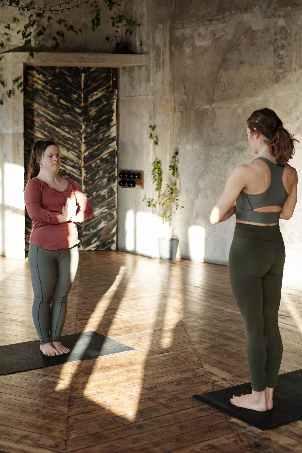 To kvinder øver yoga på et trægulv i varmt sidelys