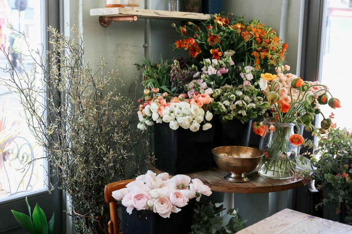 En blomsterbutik med blomster på borde og hylder ved store vinduer