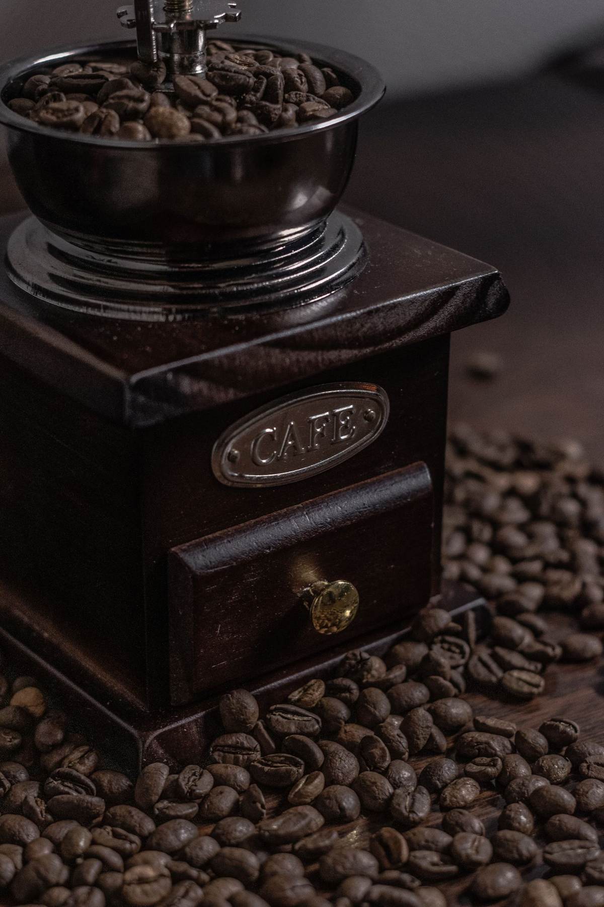 En gammeldags kaffekværn omgivet af kaffebønner