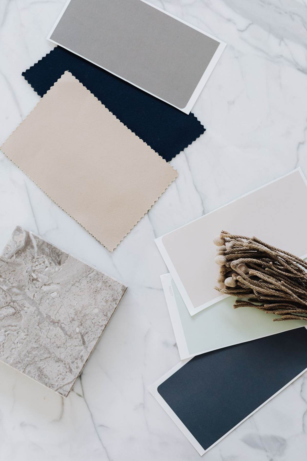 Stofprøver og materialeprøver i beige og mørkeblå på hvid marmor