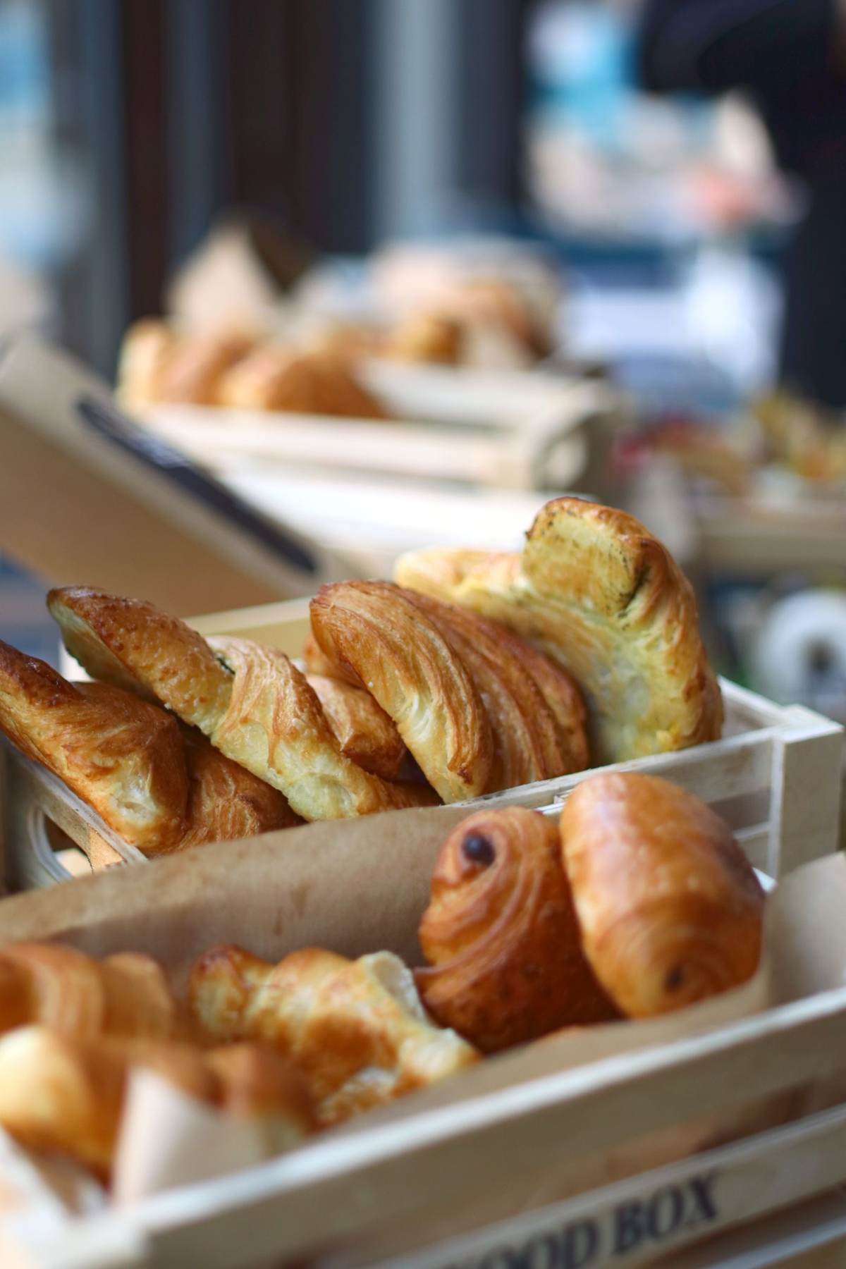 Gyldne croissanter og wienerbrød i en træbakke