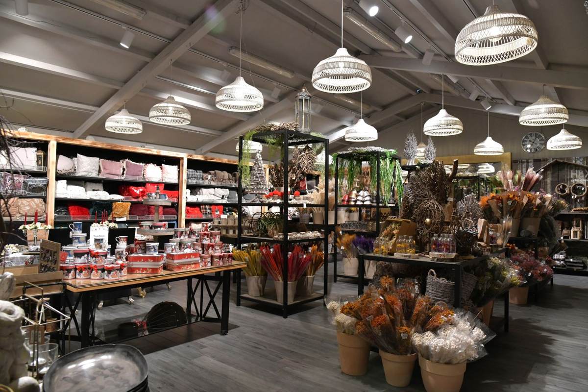 En stor blomsterbutik med hylder, lamper og borde fyldt med blomster