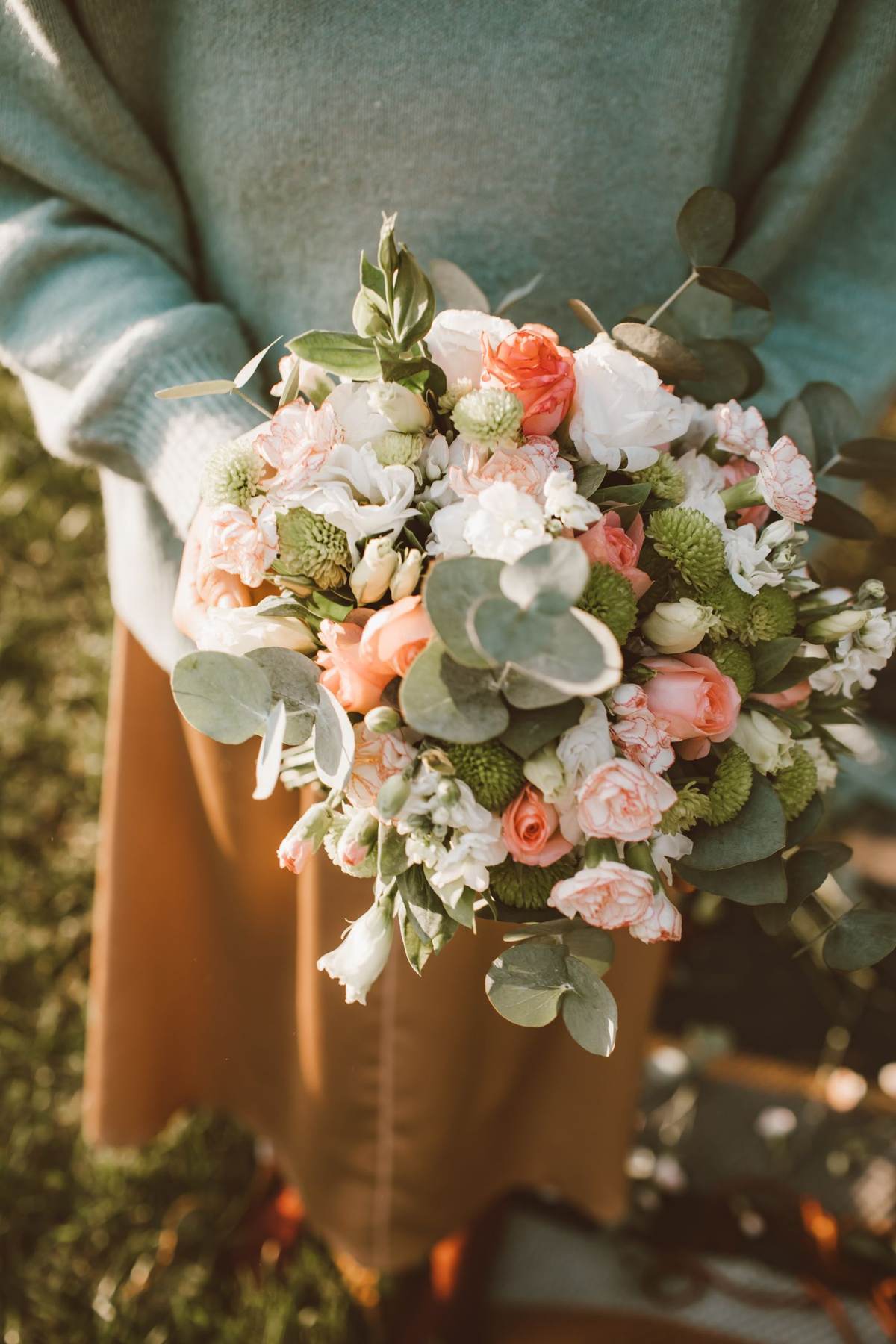 En person holder en buket med lyse blomster i hånden