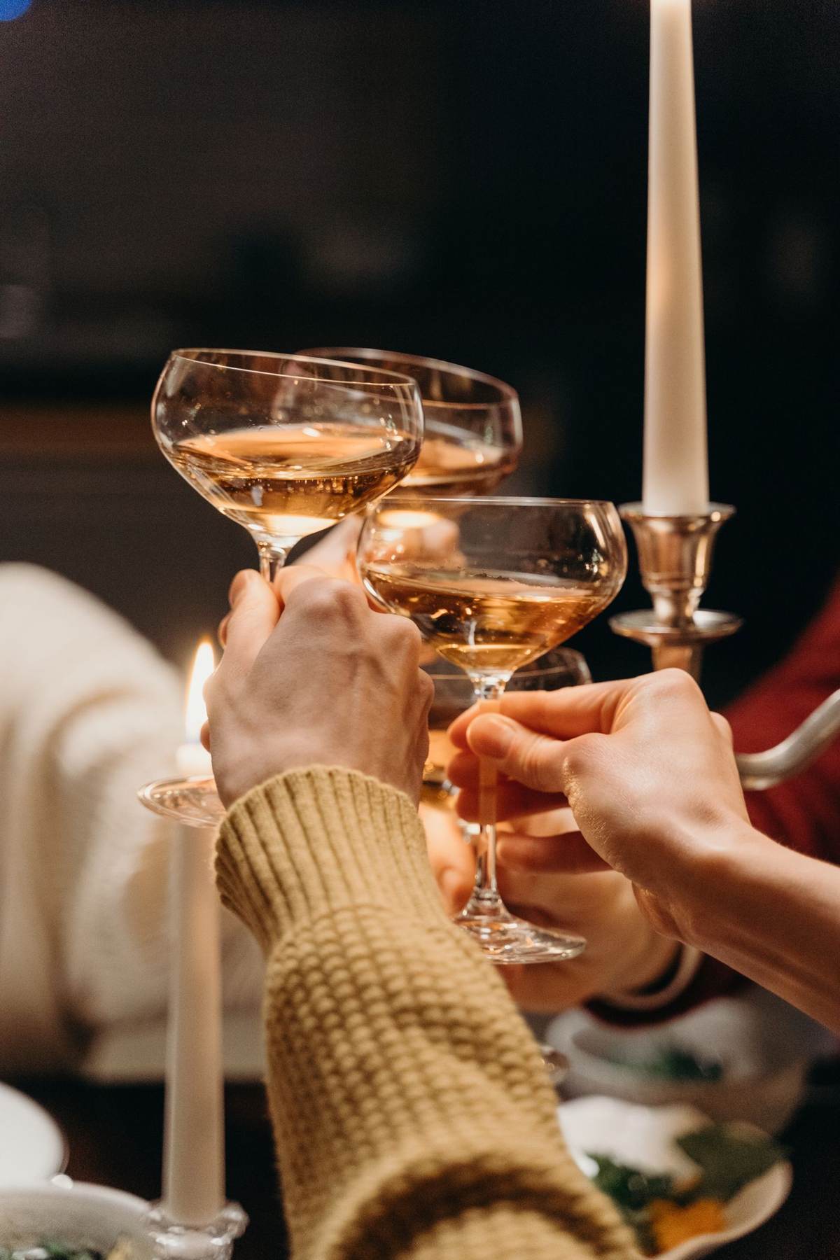 Hænder skåler med glas ved stearinlys på et bord