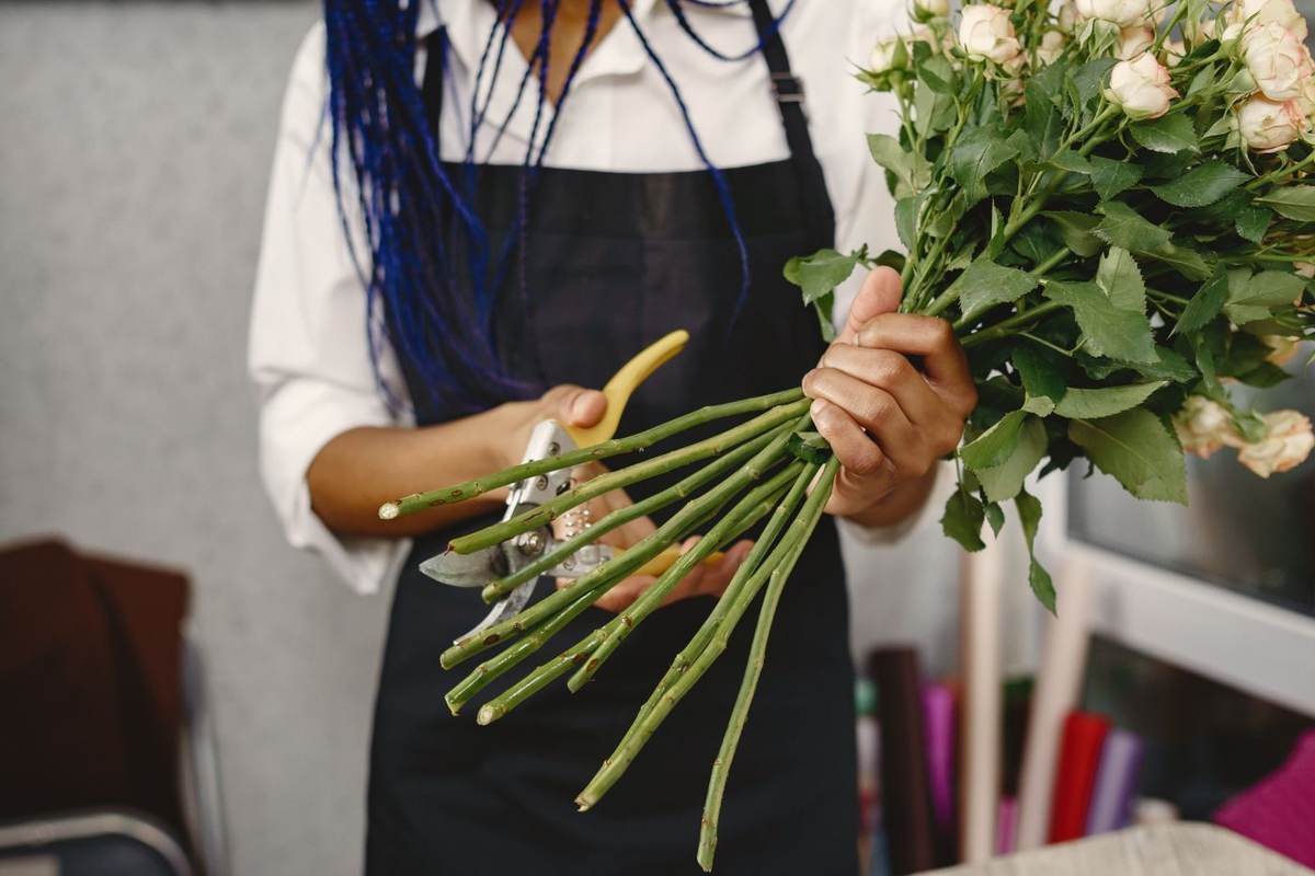 En blomsterbinder i sort forklæde holder et stort bundt lange roser
