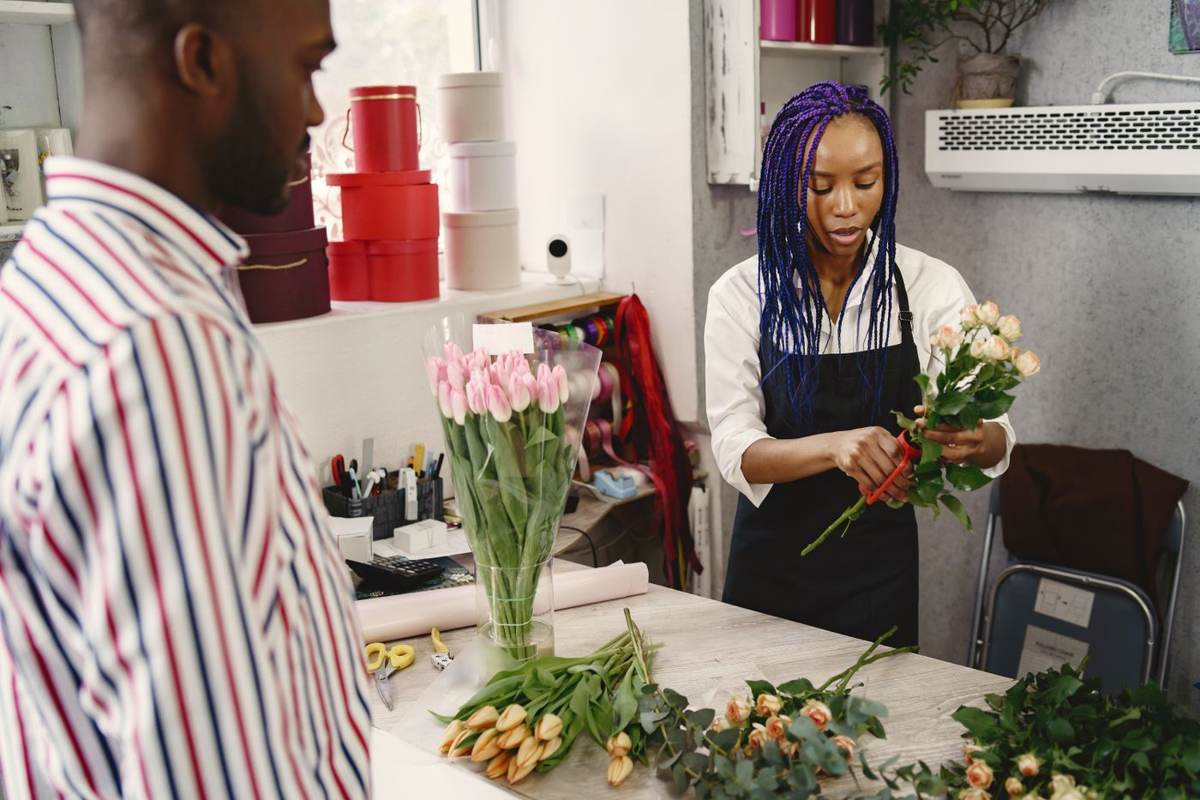 En kunde og en blomsterbinder står ved disken med en buket mellem sig