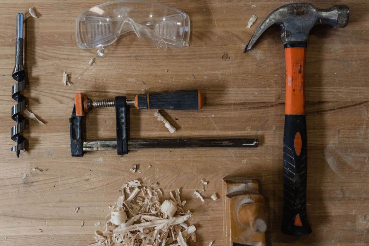 Værktøj, tvinger og høvlspåner på en træplade set ovenfra